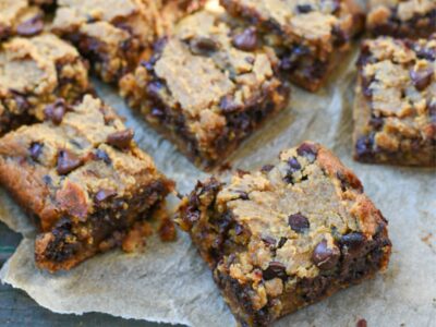 A bunch of chickpea blondie squares on parchment paper over a blue rustic wooden surface
