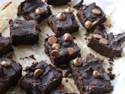 Black bean brownie spread out on parchment paper and sprinkled with chocolate chips