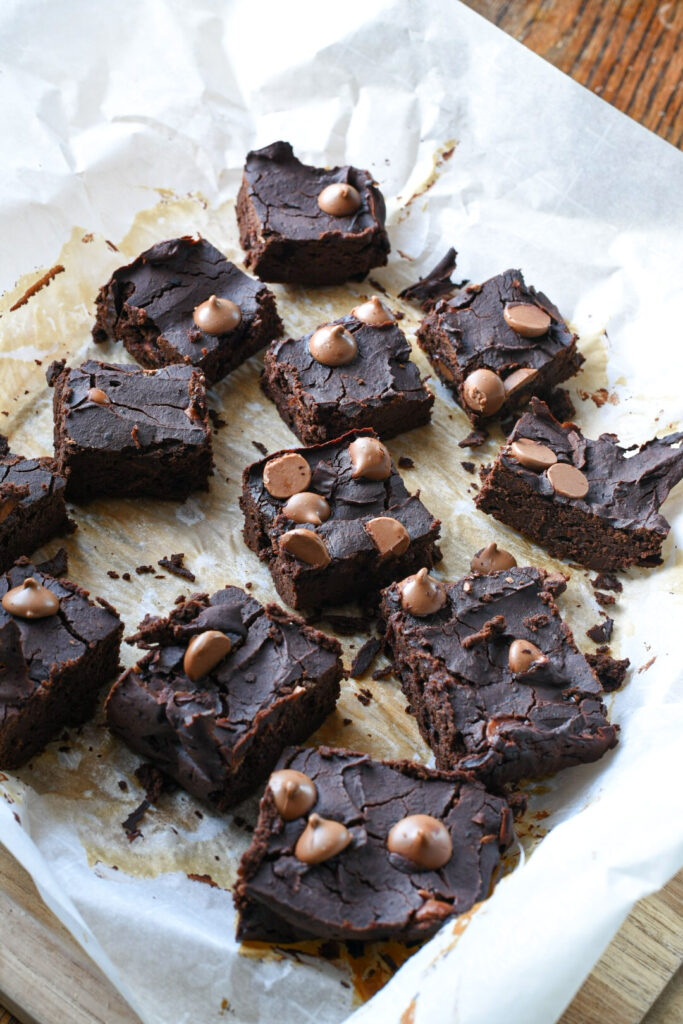 Black bean brownie spread out on parchment paper and sprinkled with chocolate chips
