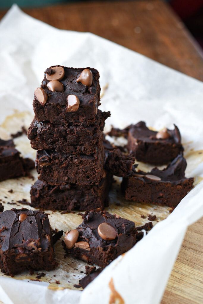 A stack of black bean brownies on parchment paper sprinkled with chocolate chips