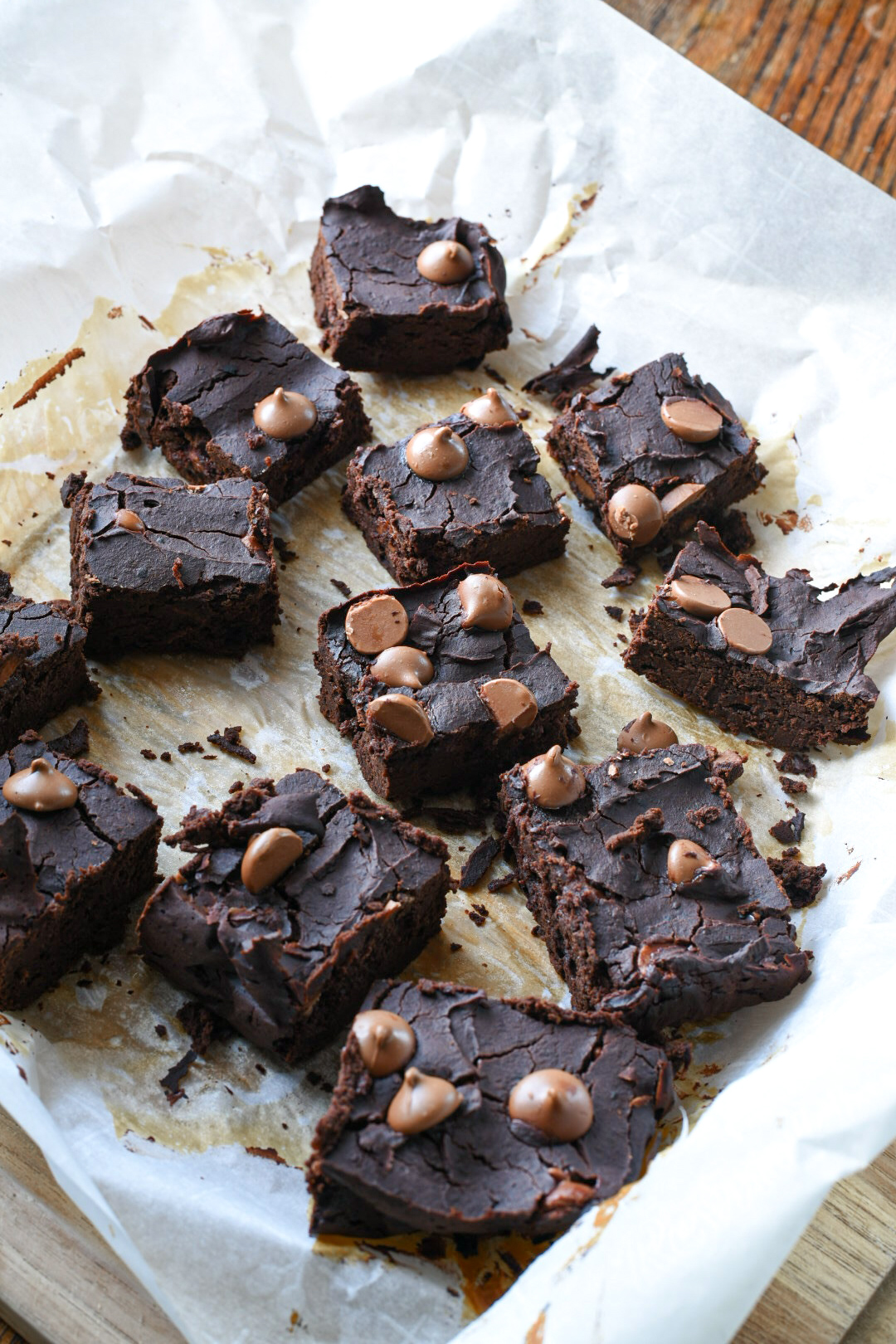 Black bean brownie spread out on parchment paper and sprinkled with chocolate chips