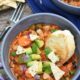 Rustic bowl of the ultimate vegan chili with carrots, lentils, beans, avocado and red onion.