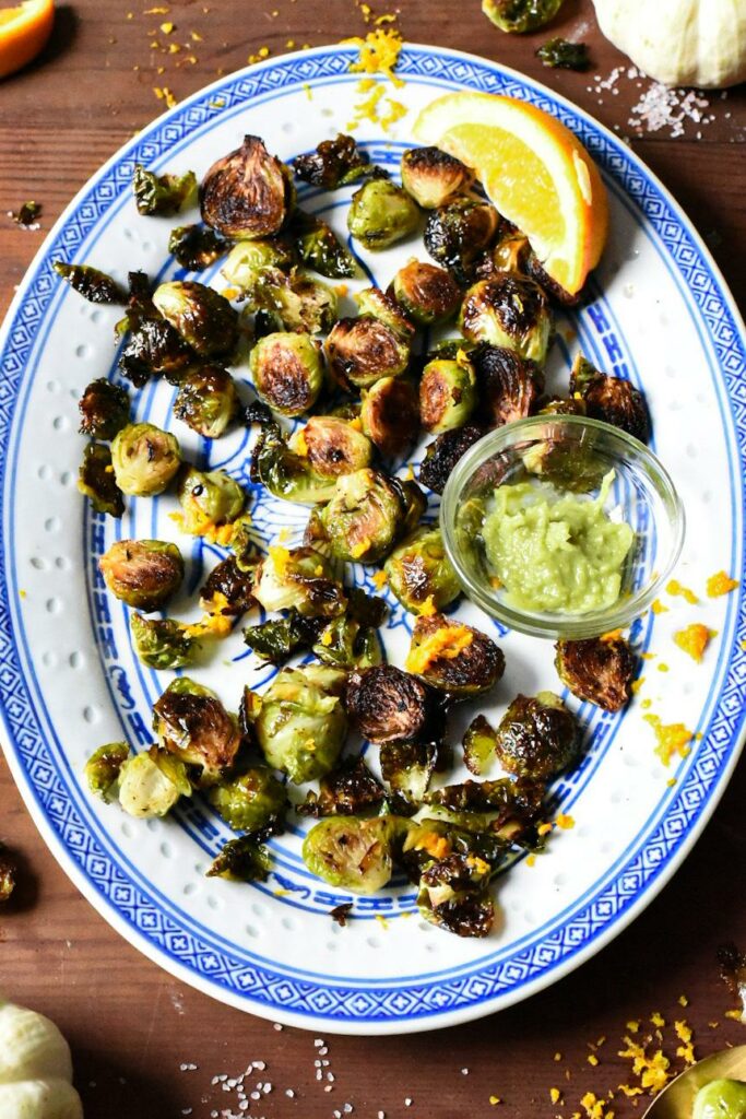 A blue and white platter with oven roasted wasabi brussels sprouts with a side of wasabi.