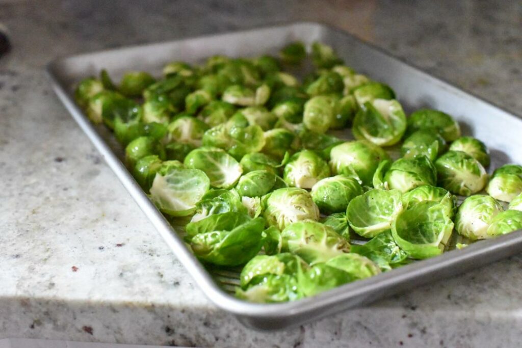brussels sprouts on a metal baking sheet on white granite countertops