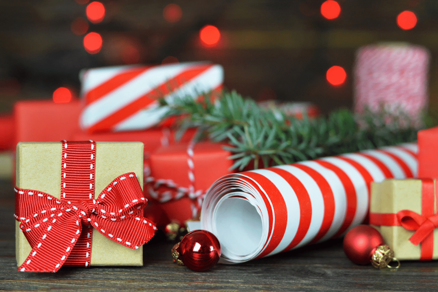 A small Christmas present next to white and red stripped wrapping paper and a red ornament