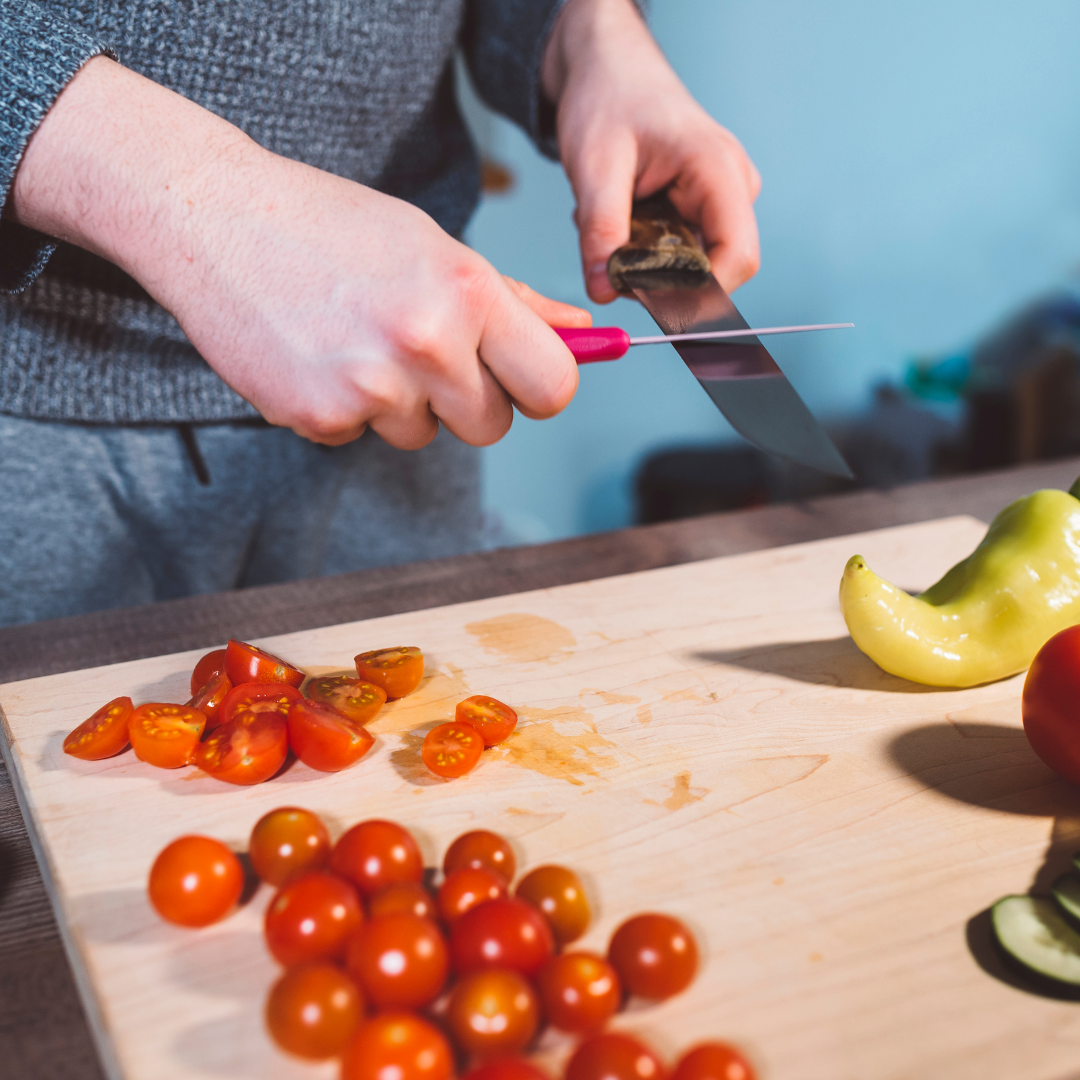 Someone holding a knife and sharpening it over a cutting board.