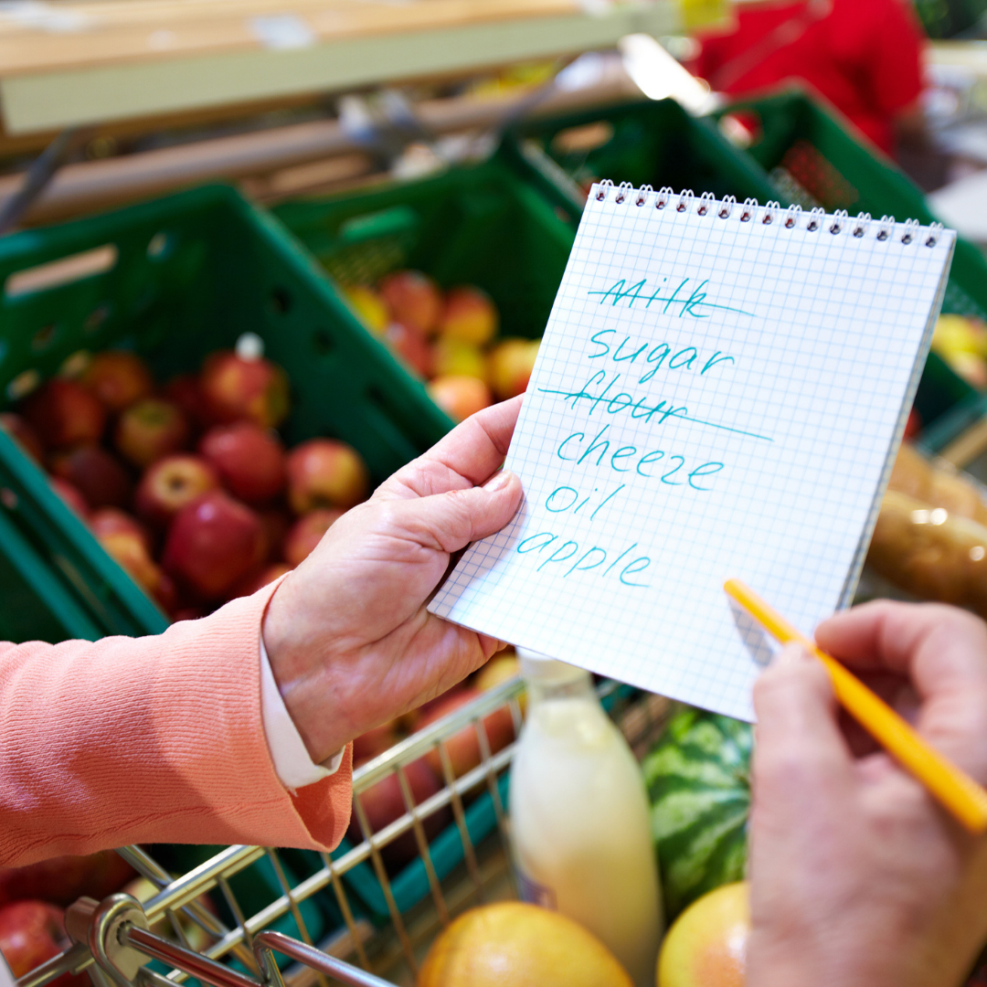 Hands holding a grocery list at a grocery store.