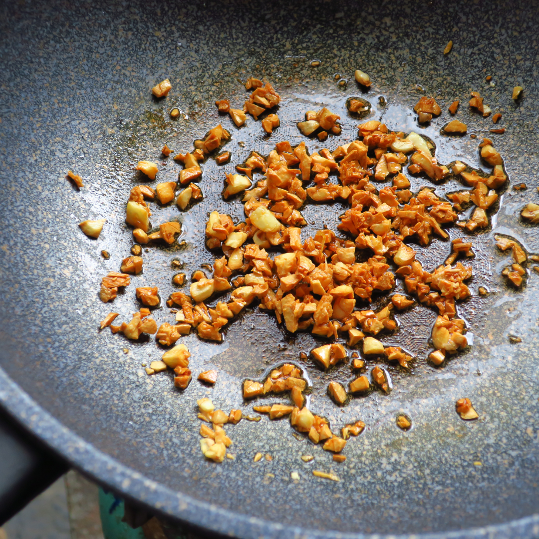 Chopped garlic searing in a non-stick pan.