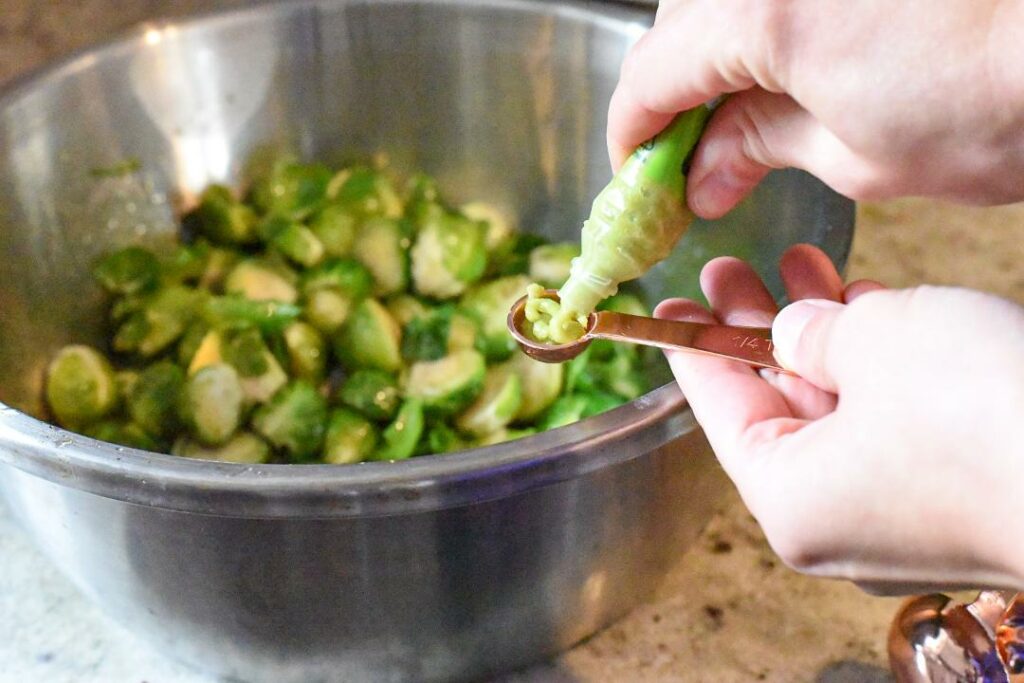 Someone squeezing wasabi paste into a measuring spoon for wasabi brussels sprouts