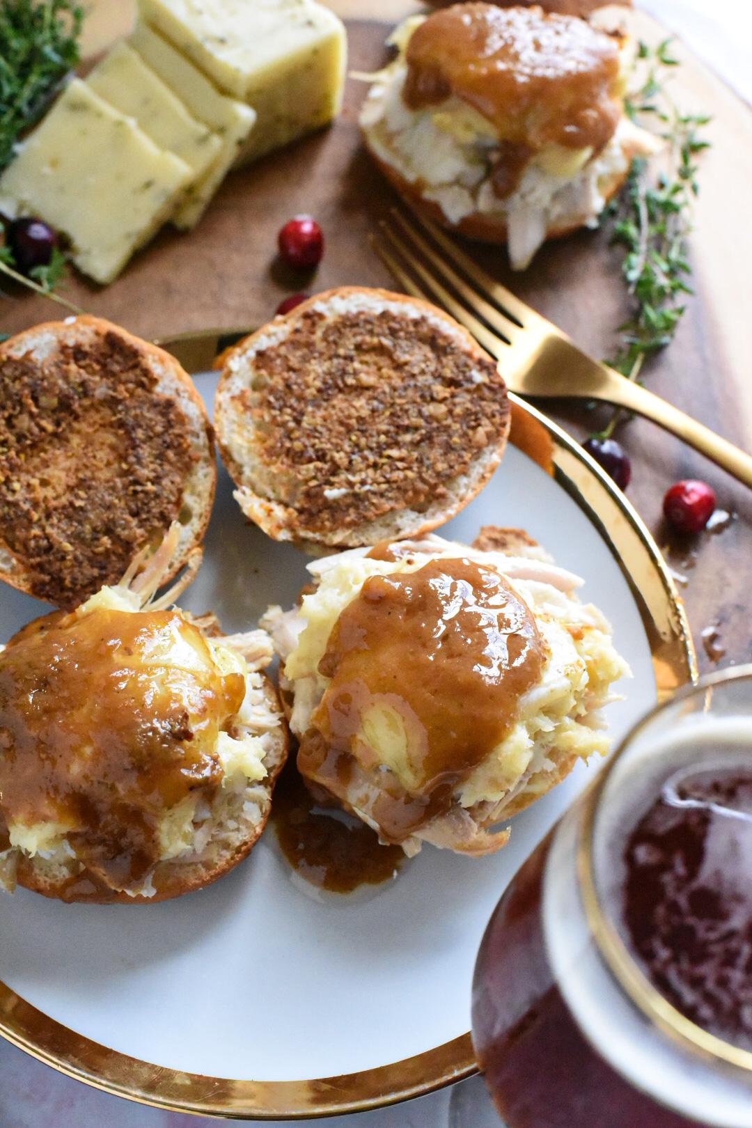 Two open faced turkey sliders on small dinner rolls, with a dollop of gravy on top and mustard on the top of the buns.
