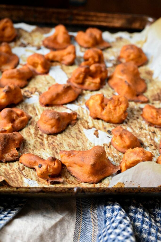 baked red buffalo cauliflower wings on a parchment paper lined baking sheet