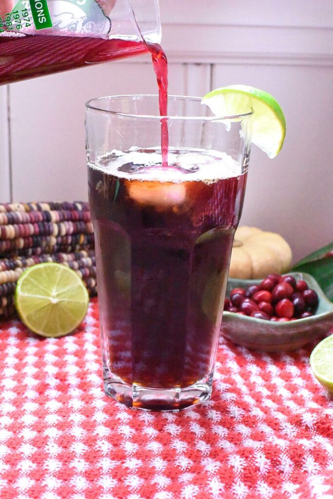 pouring cranberry juice into a coffee tonic cocktail 
