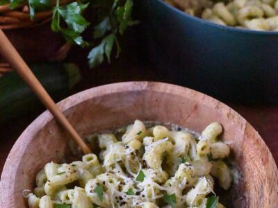easy zucchini mac and cheese in a wooden bowl with a gold fork.