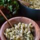 easy zucchini mac and cheese in a wooden bowl with a gold fork.