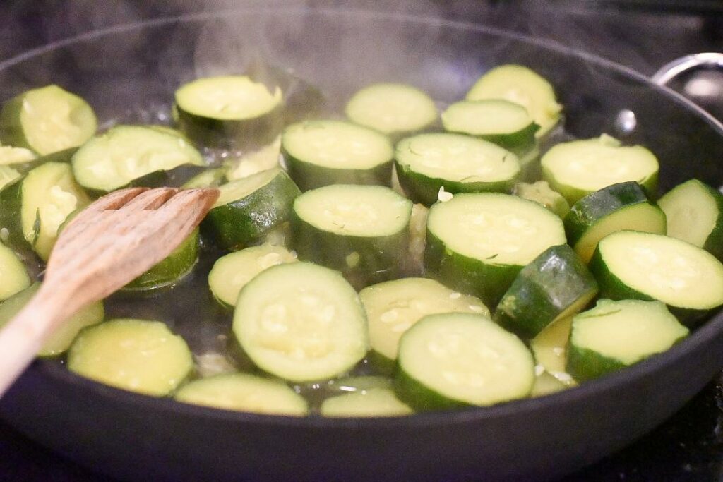Zucchini medallions being sauteed in a nonstick skillet.