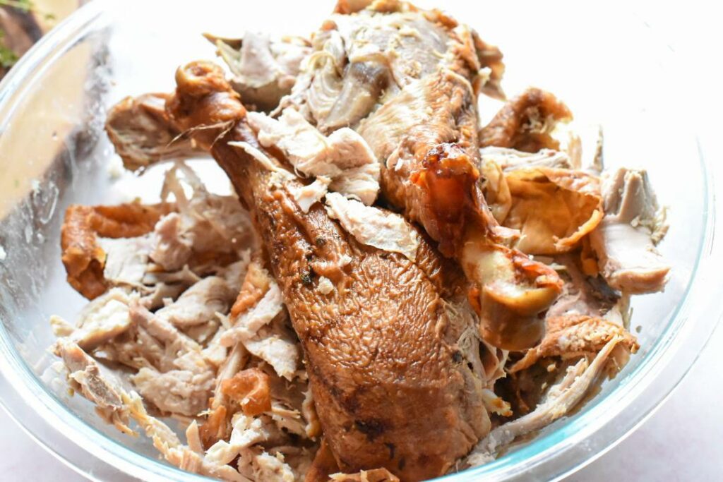 A glass bowl filled with leftover turkey.