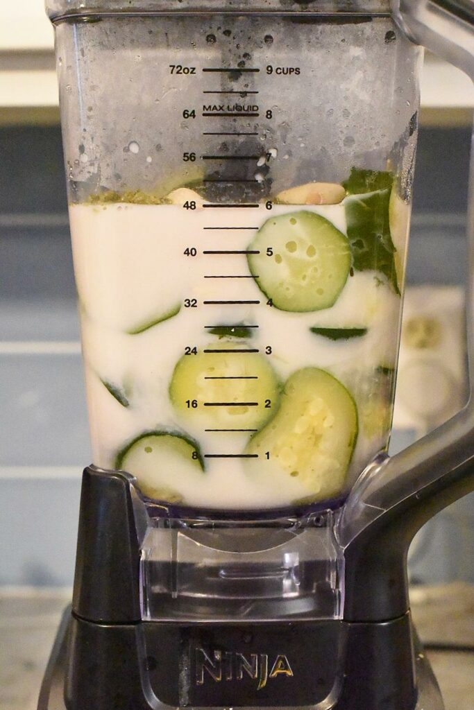Zucchini in a blender filled with milk and ingredients for zucchini mac n cheese.