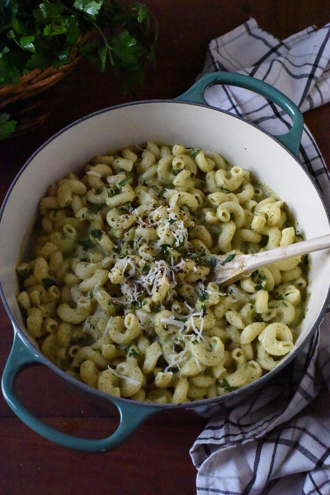 A large blue dutch oven filled with a cheesy zucchini mac n cheese recipe.