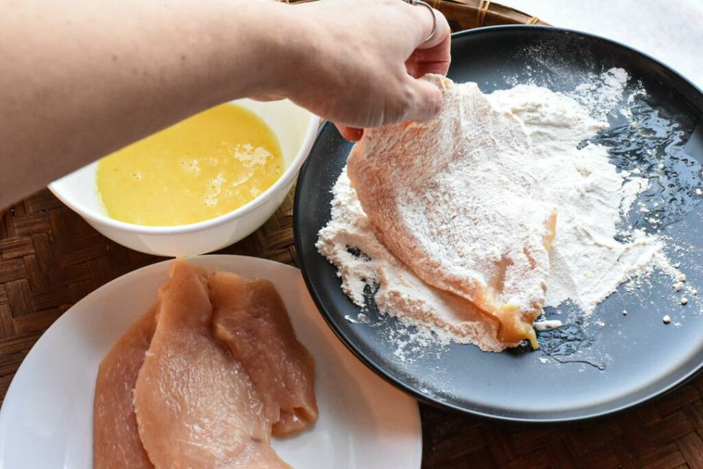 dredging boneless chicken breast in flour after dipping in egg