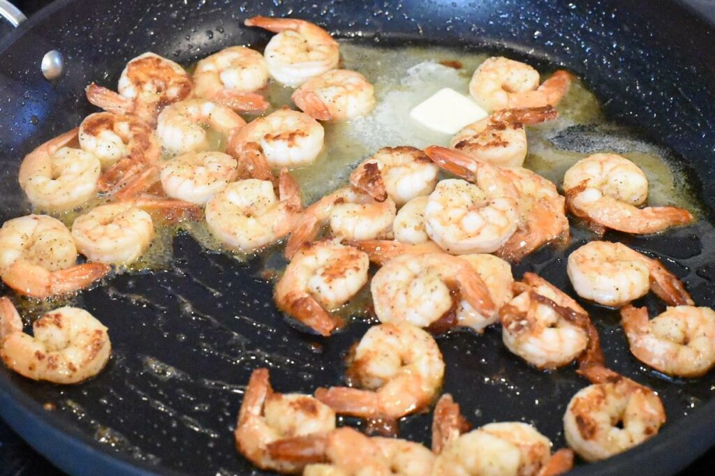 Cooked shrimp in a skillet with butter.