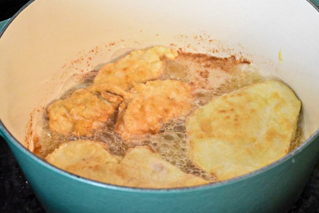 frying fried korean chicken in a blue dutch oven on the stove