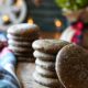 Two stacks of soft gingerspap cookies sprinkled with sugar on a wooden board with christmas lights behind