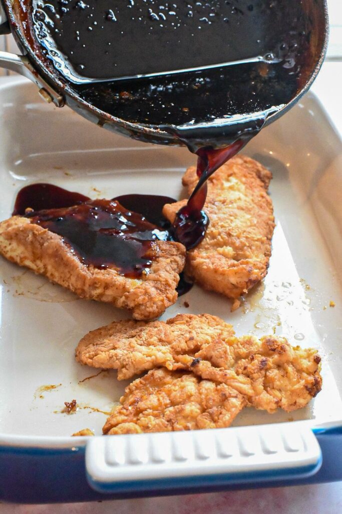 pouring korean chicken sauce over fried chicken breasts