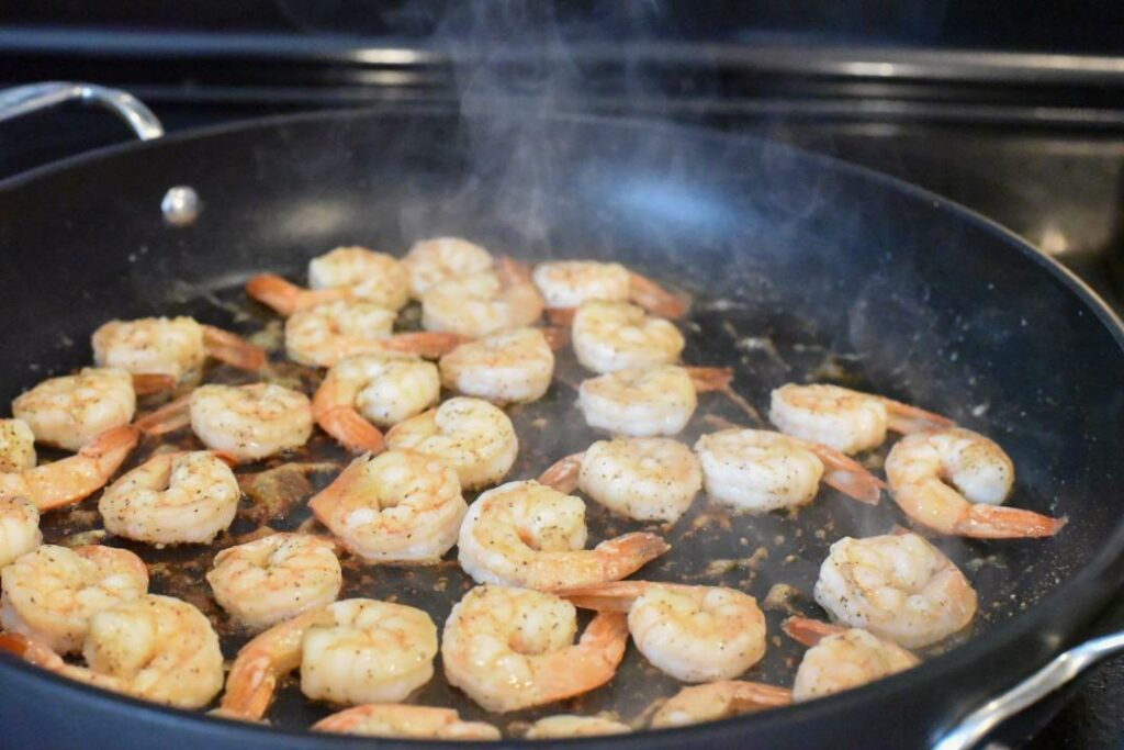 Pink shrimp in a nonstick skillet on the stove.