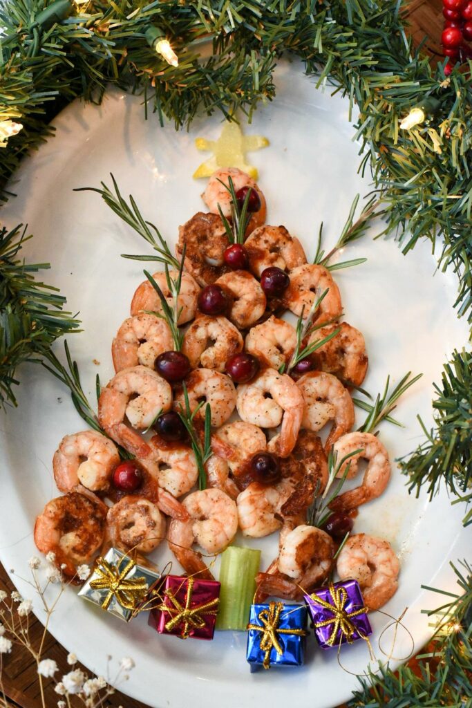 A shrimp christmas tree appetizer on a white platter with mini presents under it.