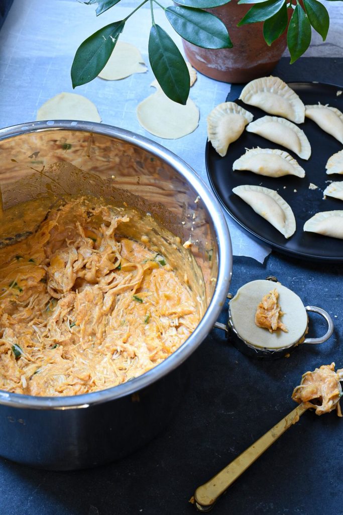 Instant pot filled with buffalo chicken dip with pierogies in the background