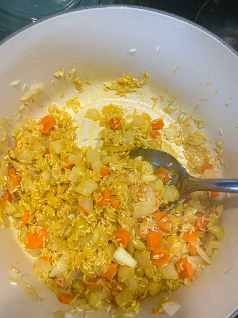a pot filled with cooking rice, carrot and onion