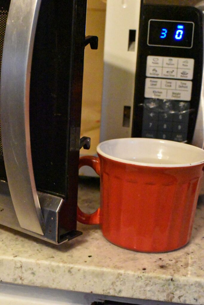 A mug cake being put into a microwave