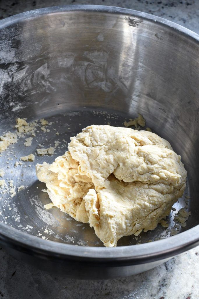 A ball of pierogi dough inside of a large metal bowl