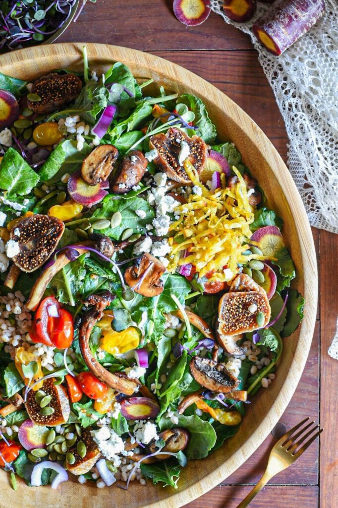 An overhead shot of a large wooden serving bowl willed with mushroom and kale winter salad.
