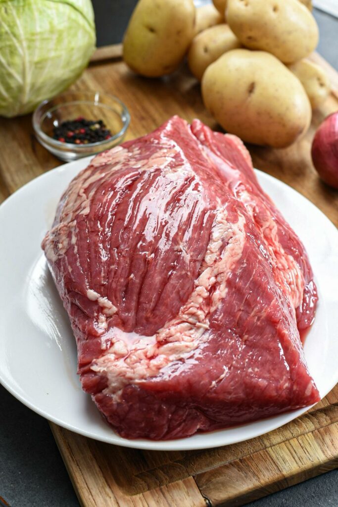 Raw corned beef brisket on a white plate 