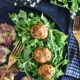 chipotle chicken meatballs on a black plate with salad