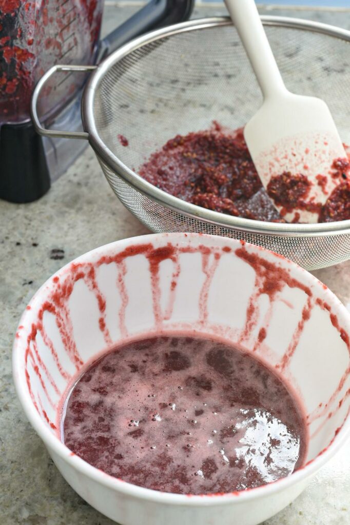 A cucumber blackberry mixture after it was blended and strained into a white bowl