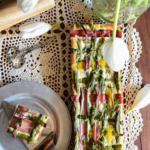 A vegetable lattice puff pastry tart with woven vegetables and egg whites on a lace table runner.