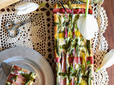 A vegetable lattice puff pastry tart with woven vegetables and egg whites on a lace table runner.