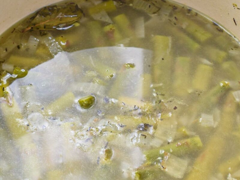 Asparagus in a large pot with broth over it being cooked for no milk asparagus soup.