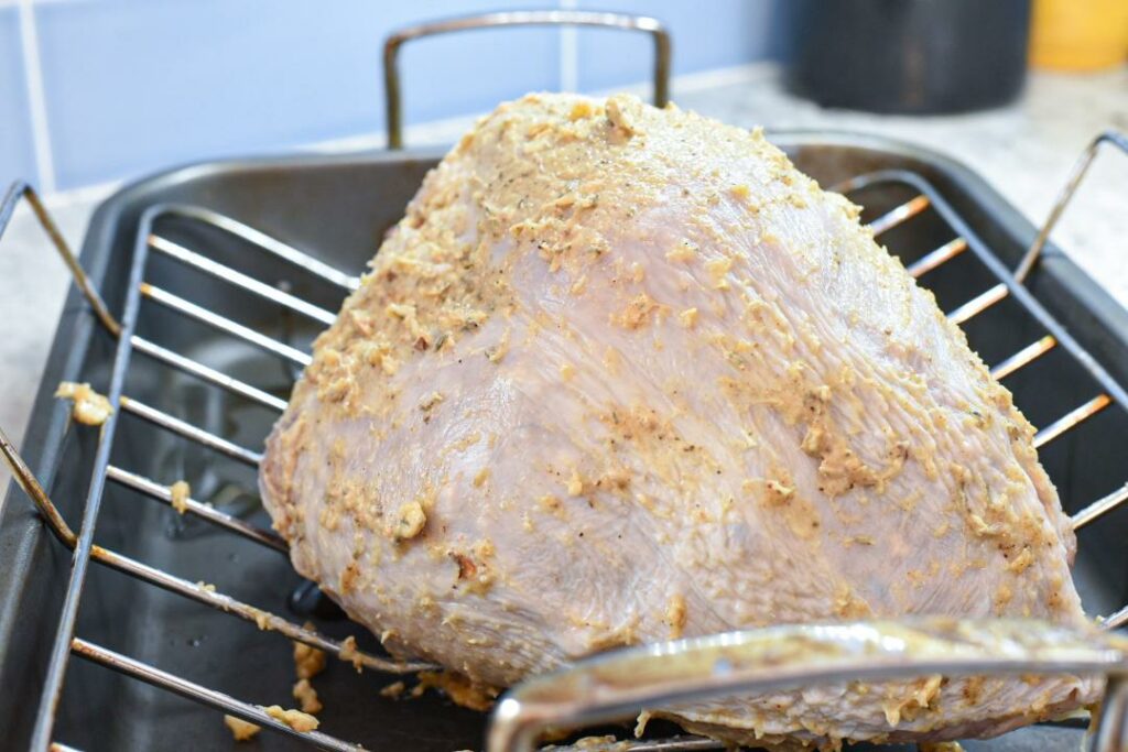 A raw turkey covered in butter in a turkey pan.