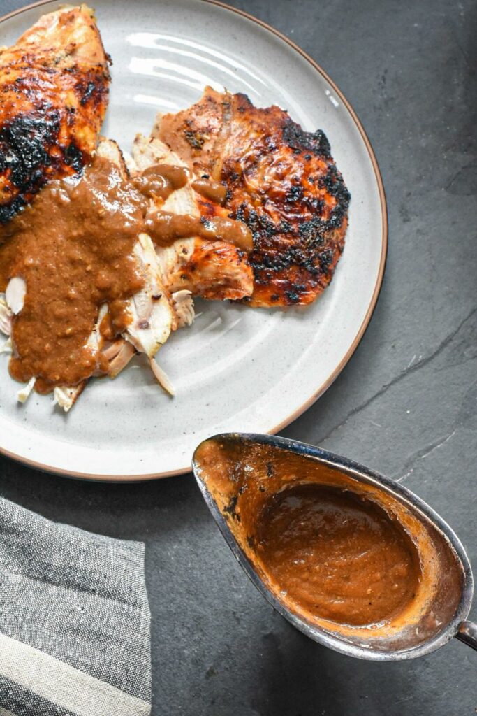 A plate of cooked skin on turkey covered in jerk sauce.