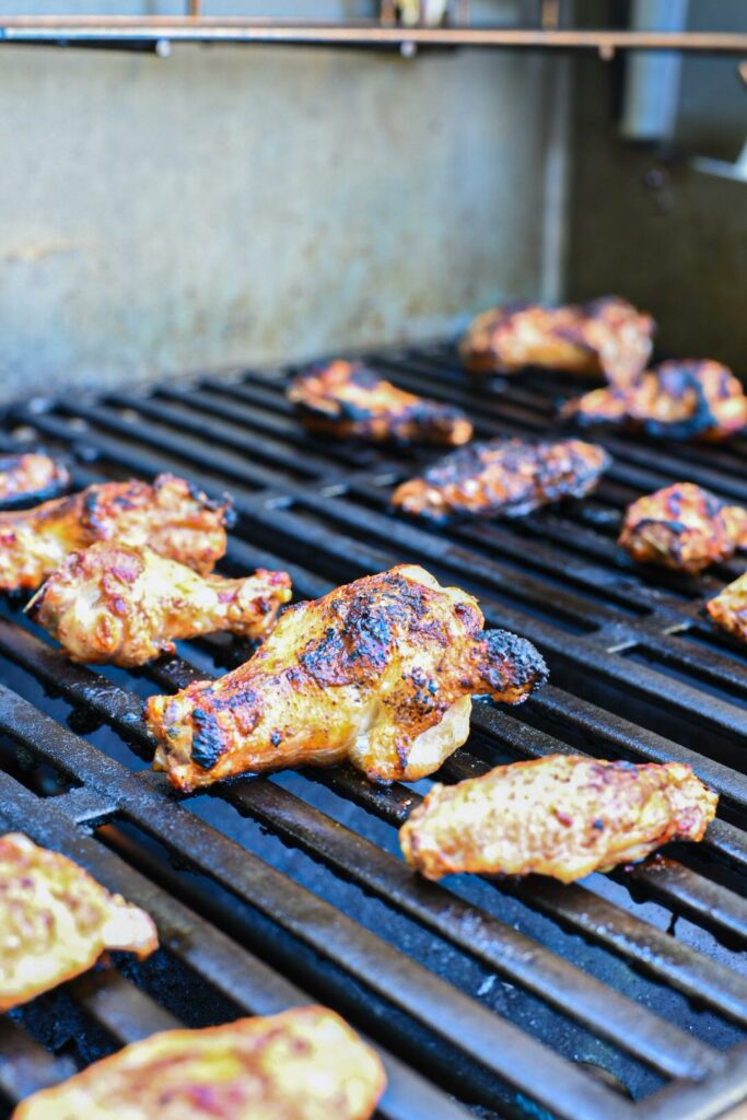 Chicken wings charred on an outdoor gas grill.