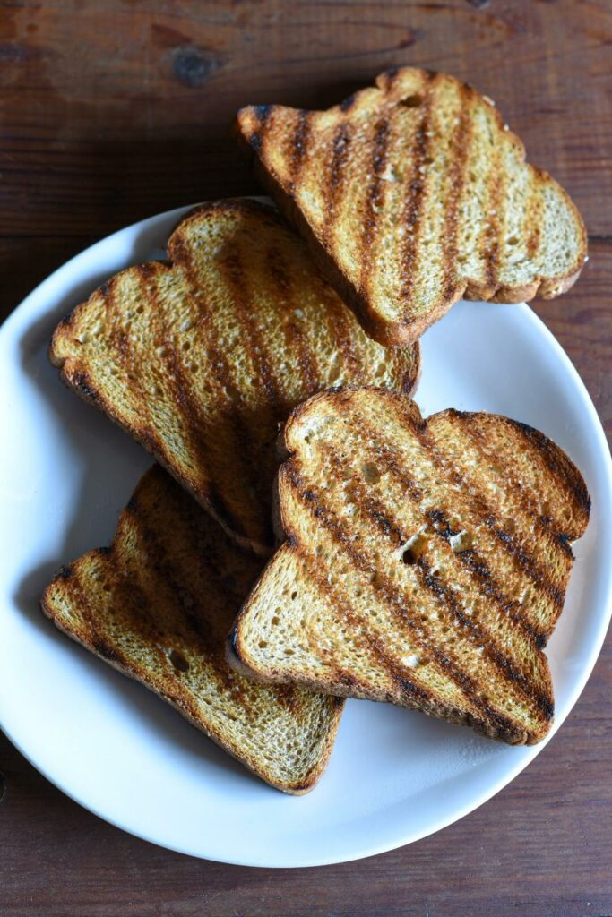 4 pieces of whole wheat bread with grill marks at an angle on each piece of bread.