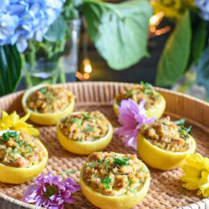 crab cake stuffed lemons on a tray with blue and green flowers behind it