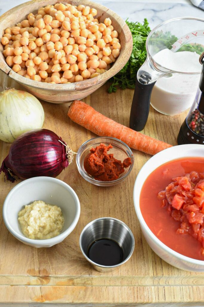 All of the ingredients needed to make freezable coconut chickpea curry on a wooden cutting board.