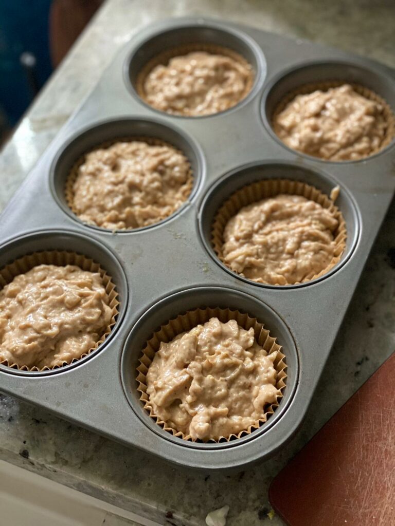 Cinnamon apple muffin batter inside muffin tins on the counter.