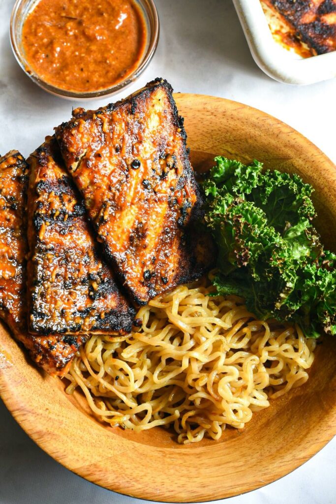 chipotle grilled tofu on noodles with kale in a wooden bowl