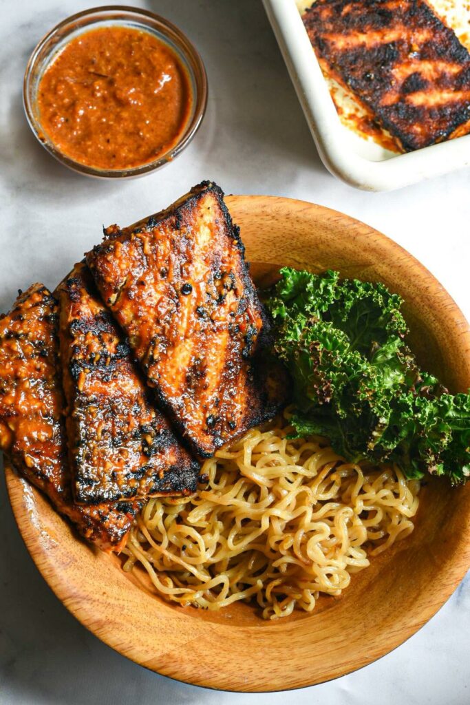 an overhead shot of grilled tofu steaks on noodles and kale