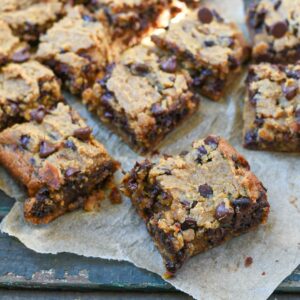 Squares of chickpea blondies on parchment paper sprinkled with chocolate chips